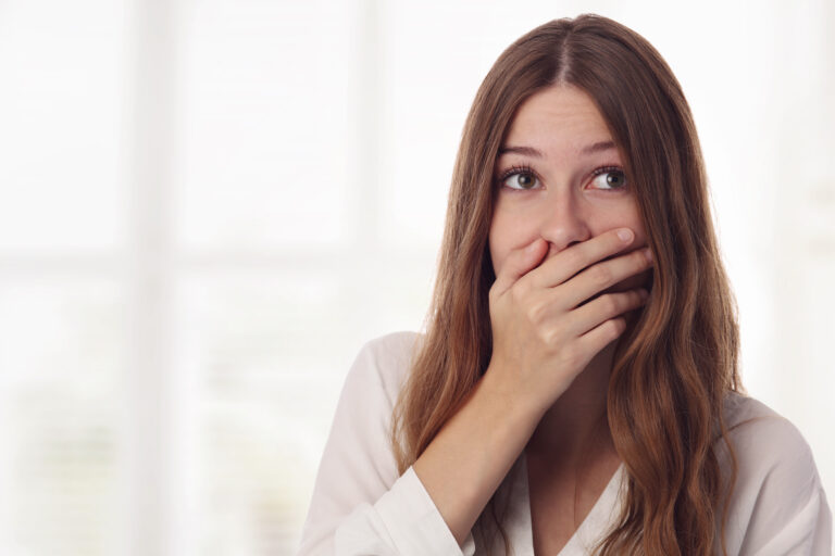 Playful, surprised, shy young woman hiding her face laughing timid.